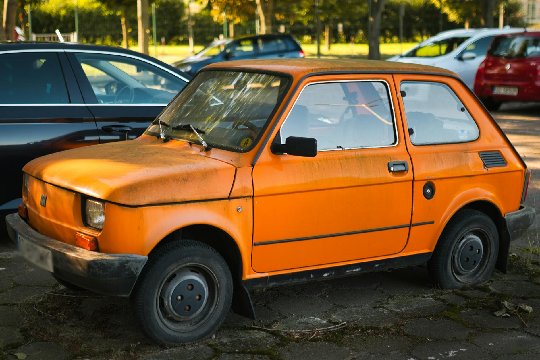 Pomarańczowy Fiat 126p zaparkowany na słońcu przed testem mikroaut